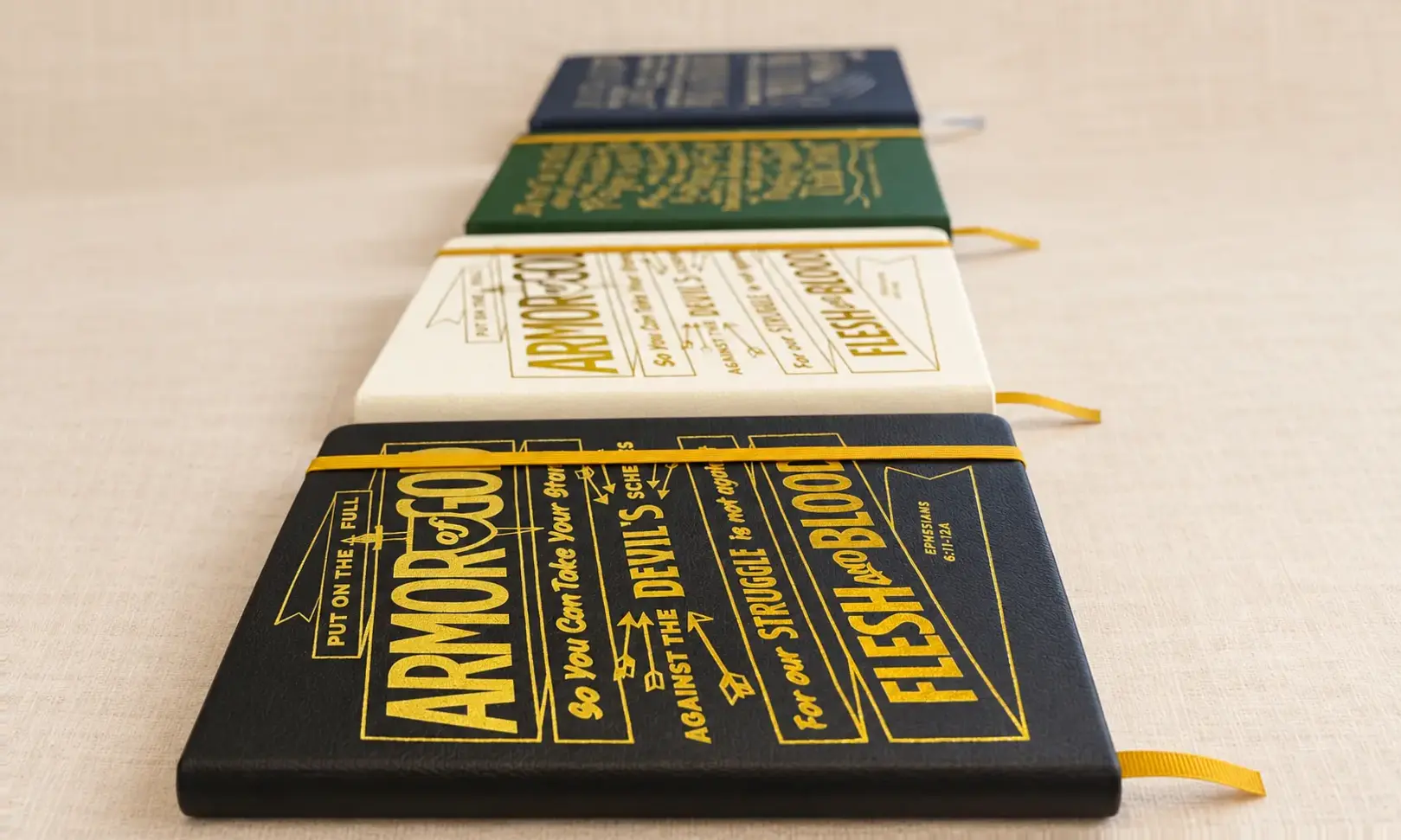 Close-up of all four Gospelis journals showing their vegan-leather texture, foil artwork, elastic closures, and ribbons