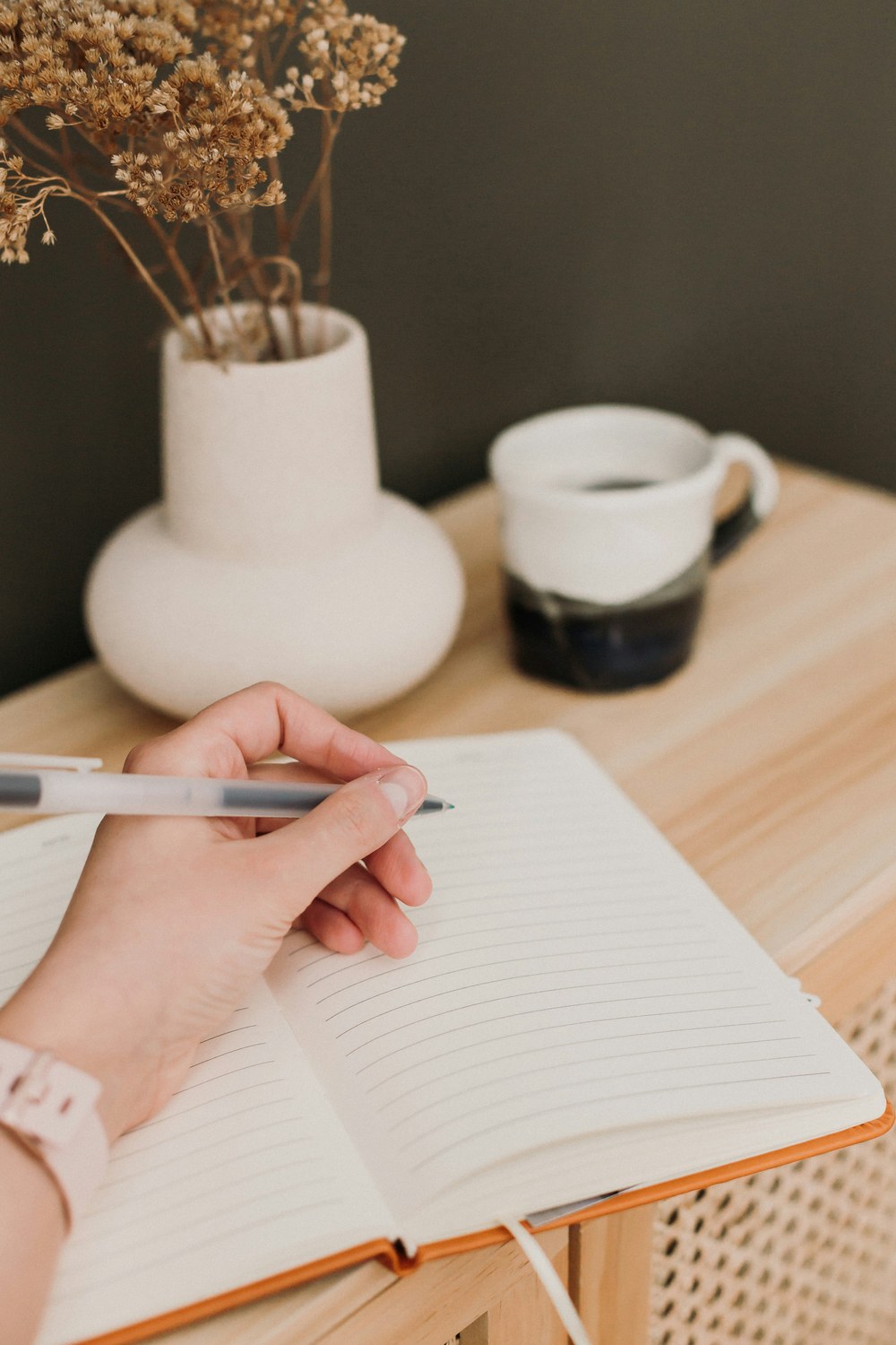 Hand writing in an open journal on a wooden desk with faint ruled lines